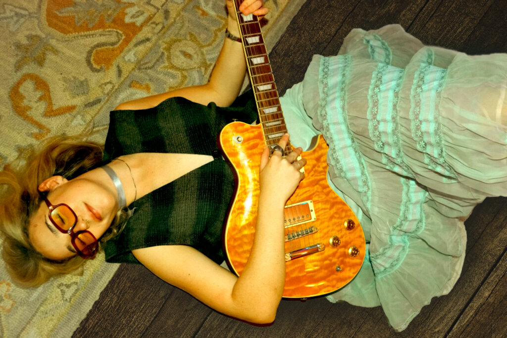 Nancy playing guitar laying on the floor